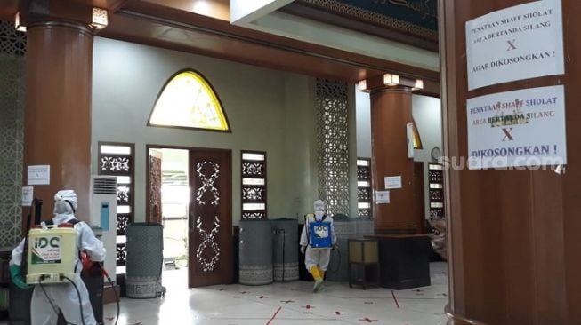 Petugas berpakaian APD lengkap saat menyemprot disinfektan di Masjid Agung Al Barkah Kota Bekasi. (Suaracom/Bagaskara).