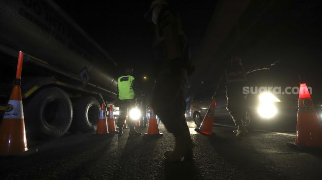 Petugas gabungan melakukan penjagaan kendaraan yang melintas di Tol Cikampek menuju Jakarta KM 47, Karawang, Jawa Barat, Kamis (28/5). [Suara.com/Angga Budhiyanto]