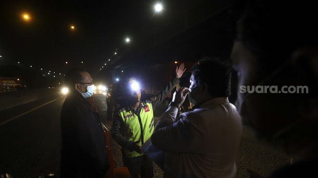 Petugas gabungan memeriksa Surat Ijin Keluar Masuk (SIKM) kepada pegendara yang melintas di Tol Cikampek menuju Jakarta KM 47, Karawang, Jawa Barat, Kamis (28/5). [Suara.com/Angga Budhiyanto]