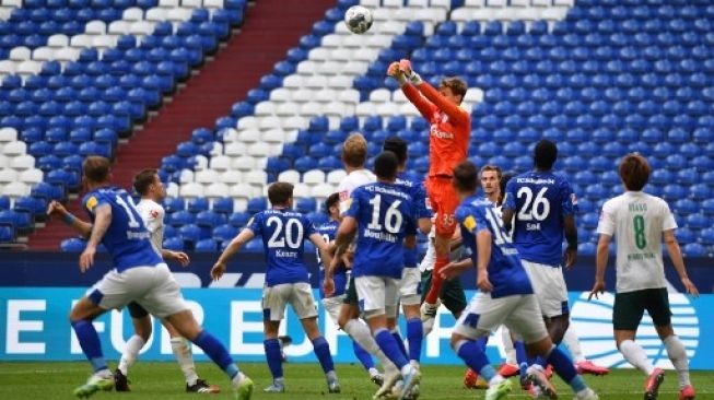 Penjaga gawang Werder Bremen meninju bola ke udara dalam pertandingan menghadapi Schalke di Veltins Arena, Sabtu (30/5/2020). [AFP]