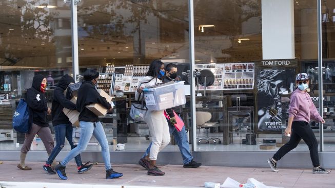 Sejumlah massa membawa barang hasil jarahanya di pusat perbelanjaan Grove di Fairfax District of Los Angeles, Amerika Serikat, Sabtu (30/5). [VALERIE MACON / AFP]