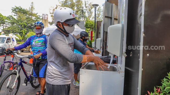 Warga diwajibkan mencuci tangan saat memasuki Kompleks Olahraga Gelora Bung Karno, Jakarta Pusat, Minggu (31/5). [Suara.com/Alfian Winanto]