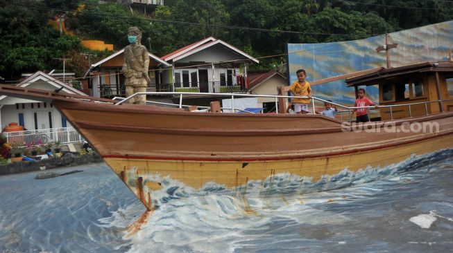 Anak-anak bermain di dekat patung Syamsul Bahri yang dipasangkan masker di Batang Arau, Padang, Sumatera Barat, Sabtu (30/5). [ANTARA FOTO/Iggoy el Fitra]