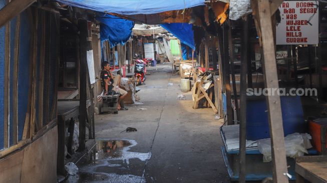 Pedagang berjaga dideretan warung yang tutup di Pasar Cisalak, Depok, Jawa Barat, Minggu (31/5). [Suara.com/Alfian Winanto]