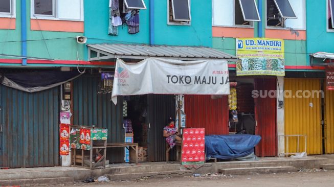 Pedagang sembako bersantai didepan kiosnya  yang tutup di Pasar Cileungsi, Bogor, Jawa Barat, Senin (1/6). [Suara.com/Alfian Winanto]