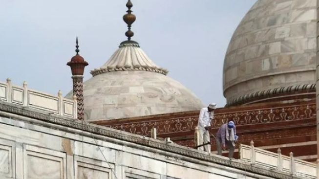 Para pekerja meninjau pagar Taj Mahal yang rusak akibat hantaman badai yang melanda India Utara. (AFP)