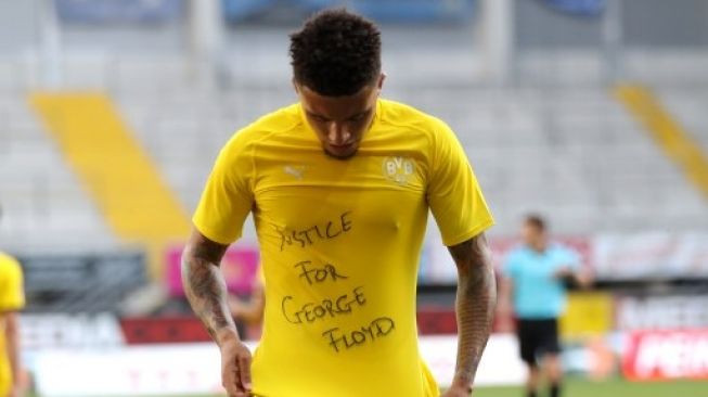 Gelandang Borussia Dortmund Jadon Sancho menunjukkan tulisan "Justice for George Floyd" saat merayakan golnya ke gawang Paderborn dalam lanjutan Liga Jerman. Lars Baron / POOL / AFP