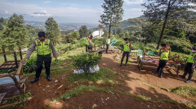 Sejumlah petugas kepolisian menutup lapak pedagang kaki lima yang ada di kawasan wisata Puncak di Kabupaten Bogor, Jawa Barat, Senin (1/6). [ANTARA FOTO/Yulius Satria Wijaya]
