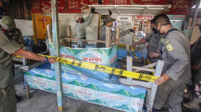 Sejumlah petugas Satpol PP menyegel warung pedagang kaki lima (PKL) yang masih buka di kawasan Puncak, Kabupaten Bogor, Jawa Barat, Senin (1/6). [ANTARA FOTO/Yulius Satria Wijaya]