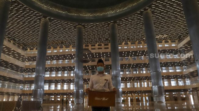 Petugas memindahkan kotak amal di Masjid Istiqlal, Jakarta Pusat, Selasa (2/6). [Suara.com/Alfian Winanto]
