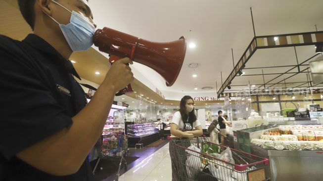 Petugas memberi imbauan kepada pengunjung untuk tetap menjaga jarak fisik saat berbelanja di AEON Mall, Tangerang, Banten, Selasa(2/6). [Suara.com/Angga Budhiyanto]