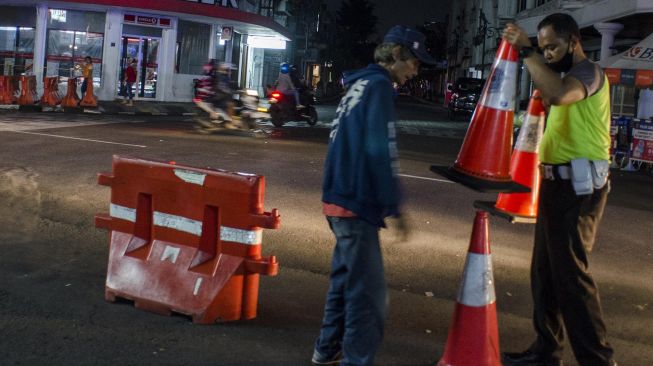 Warga membantu petugas Kepolisian menyingkirkan pembatas untuk membuka ruas jalan Kawasan Braga, Bandung, Jawa Barat, Senin (1/6). [ANTARA FOTO/Novrian Arbi]