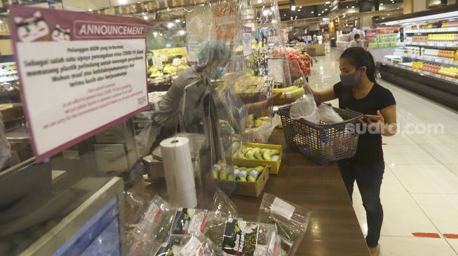 Petugas melayani konsuen dari balik sekat plastik di AEON Mall, Tangerang, Banten, Selasa(2/6). [Suara.com/Angga Budhiyanto]