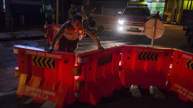 Petugas Kepolisian menyingkirkan pembatas untuk membuka ruas jalan Kawasan Naripan, Bandung, Jawa Barat, Senin (1/6). [ANTARA FOTO/Novrian Arbi]