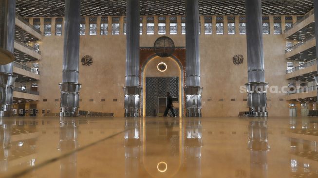 Petugas berjalan di aula utama Masjid Istiqlal, Jakarta Pusat, Selasa (2/6). [Suara.com/Alfian Winanto]