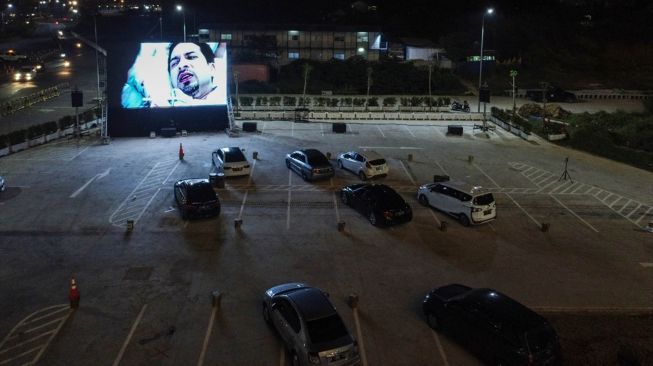 Warga menonton film yang ditampilkan di layar drive-in cinema di area parkir Meikarta Cikarang, Jawa Barat, Selasa (2/6). [Anadolu/ Anton Raharjo] 