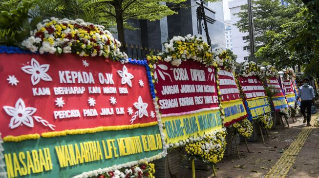 Warga melintasi karangan bunga di Pengadilan Negeri Jakarta Pusat, Jakarta, Rabu (3/6/2020).  [ANTARA FOTO/Galih Pradipta]