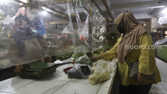 Pembeli berbelanja di lapak yang dipasangi tirai plastik di Pasar Bandeng, Kota Tangerang, Banten, Selasa (2/6). [Suara.com/Angga Budhiyanto]
