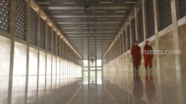 Petugas pemadam kebakaran melakukan penyemprotan cairan disinfektan di Masjid Istiqlal, Jakarta, Rabu (3/6). [Suara.com/Angga Budhiyanto]