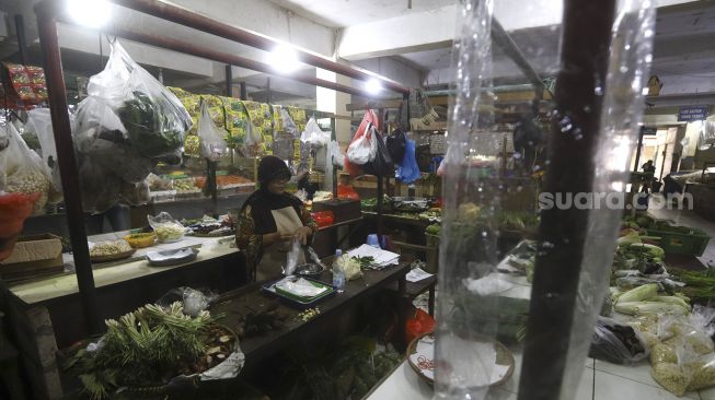 Pedagang berada di lapaknya yang dipasangi tirai plastik di Pasar Bandeng, Kota Tangerang, Banten, Selasa (2/6). [Suara.com/Angga Budhiyanto]