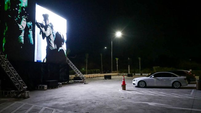 Warga menonton film yang ditampilkan di layar drive-in cinema di area parkir Meikarta Cikarang, Jawa Barat, Selasa (2/6). [Anadolu/ Anton Raharjo] 