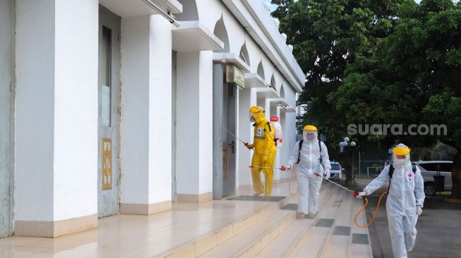 Petugas menyemprotkan cairan disinfektan area luar  Masjid Agung Al-Azhar, Jakarta Selatan, Rabu (3/6). [Suara.com/Alfian Winanto]