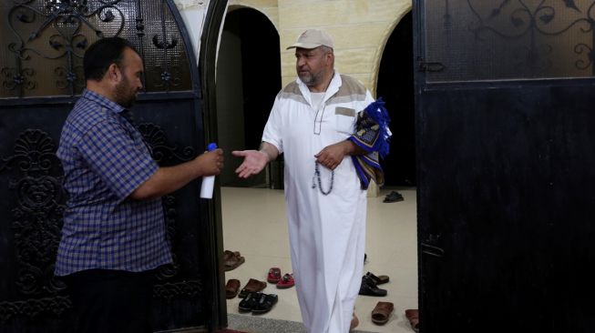 Petugas Masjid menyemprotkan Hand Sanitizer ke warga Gaza yang melakukan salat subuh berjamaah di Masjid Al-Buhari di Deir Al-Balah, Gaza pada 3 Juni 2020. [Foto/Anadolu Agency]
