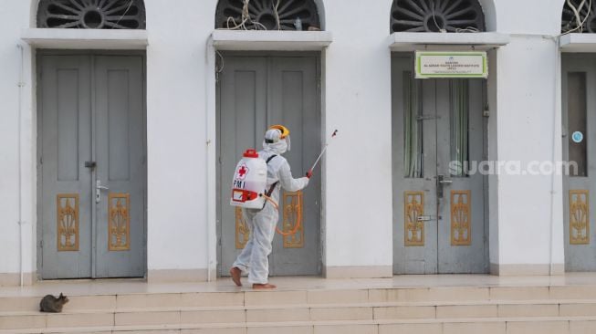 Petugas menyemprotkan cairan disinfektan area luar  Masjid Agung Al-Azhar, Jakarta Selatan, Rabu (3/6). [Suara.com/Alfian Winanto]