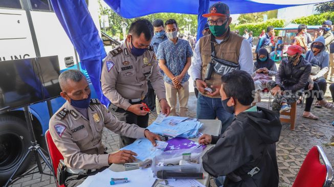 Petugas mengurus berkas perpanjangan SIM warga di Pelayanan SIM Keliling Masjid At-Tin, Jakarta Timur, Kamis (4/6). [Suara.com/Alfian Winanto]