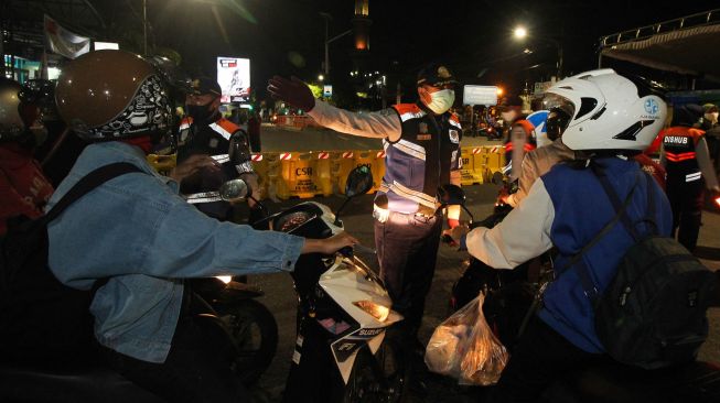 Petugas meminta pengendara kendaraan bermotor untuk berputar balik di Jalan Rungkut Menanggal, Surabaya, Jawa Timur, Kamis (4/6). [ANTARA FOTO/Didik Suhartono]