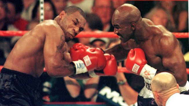 Evander Holyfield (kanan) mendaratkan pukulan keras ke wajah penantangnya, Mike Tyson, dalam duel tinju dunia di MGM Grand, Las Vegas, Sabtu (28/6/1997). Mike Tyson dinyatakan kalah pada ronde ketiga lantaran didiskualifikasi karena menggigit kuping lawannya hingga berdarah. [AFP/John Gurzinski]