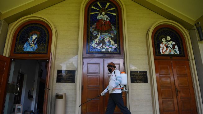 Pekerja menyemprotkan cairan disinfektan di halaman Gereja Kristus Raja, Surabaya, Jawa Timur, Jumat (5/6/2020). [ANTARA FOTO/Zabur Karuru]
