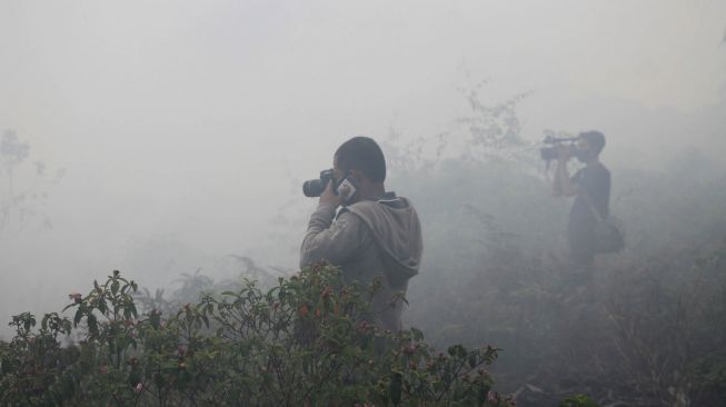 Jurnalis mengambil gambar suasana kebakaran lahan gambut di Desa Peunaga Cut Ujong, Kecamatan Meureubo, Aceh Barat, Aceh, Kamis (4/6). [ANTARA FOTO/Syifa Yulinnas]