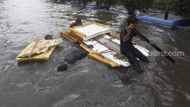 Warga naik gerobak mencoba menerobos banjir rob di kawasan Pelabuhan Nizam Zachman, Muara Baru, Jakarta Utara, Jumat (5/6). . [Suara.com/Angga Budhiyanto]
