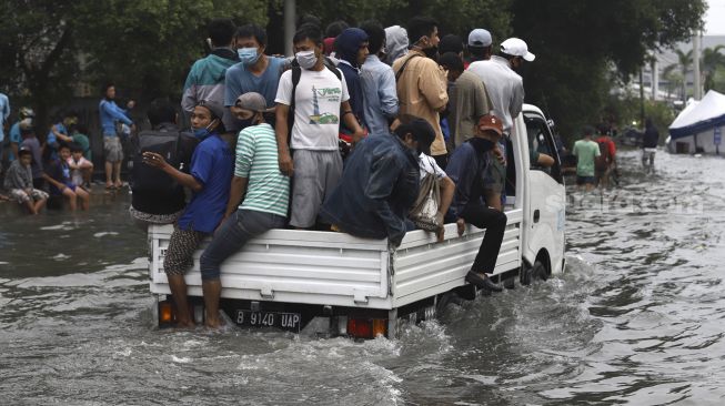 Warga naik mobil bak mencoba menerobos banjir rob di kawasan Pelabuhan Nizam Zachman, Muara Baru, Jakarta Utara, Jumat (5/6). . [Suara.com/Angga Budhiyanto]
