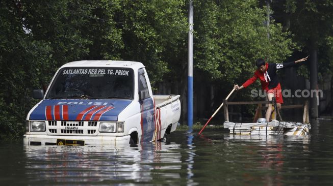 Warga naik gerobak mencoba menerobos banjir rob di kawasan Pelabuhan Nizam Zachman, Muara Baru, Jakarta Utara, Jumat (5/6). . [Suara.com/Angga Budhiyanto]
