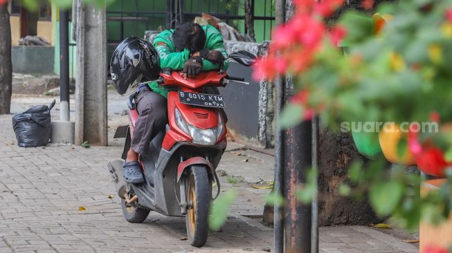 Pengemudi ojek online beristirahat saat menunggu orderan di daerah Kramat Jati, Jakarta Timur, Sabtu (6/6).  [Suara.com/Alfian Winanto]
