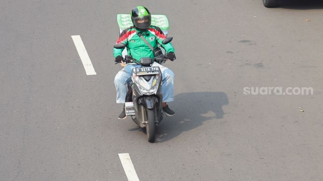 Pengemudi ojek online membawa barang di daerah Kalibata, Jakarta Selatan, Sabtu (6/6). [Suara.com/Alfian Winanto]