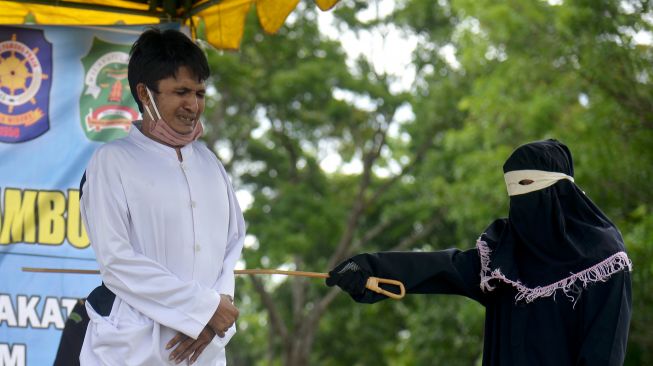 Seorang pria terpidana dalam kasus zina menjalani hukuman cambuk di Masjid Al Munawarah, Kota Jantho, Kabupaten Aceh Besar, Aceh, Jumat (5/6).   [ANTARA FOTO/Ampelsa]