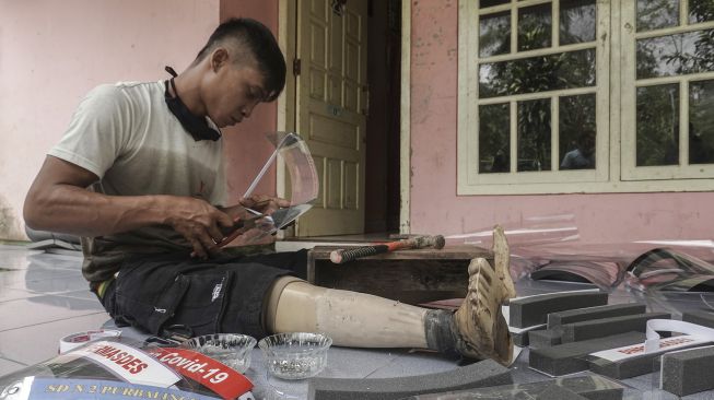 Aang Santosa (27), seorang penyandang difabel, membuat pelindung wajah pesanan dari sejumlah instasi pemkab dan masyarakat umum, di rumahnya di Desa Cipaku, Mrebet, Purbalingga, Sabtu (6/6). [ANTARA FOTO/Idhad Zakaria]