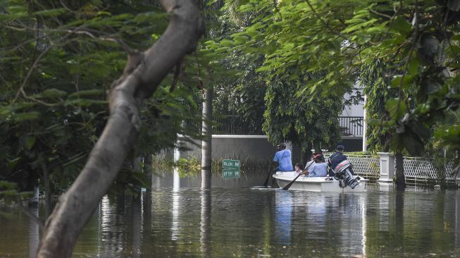 Warga menggunakan perahu untuk melintasi banjir rob di Kompleks Pantai Mutiara, Penjaringan, Jakarta, Minggu (7/6). [ANTARA FOTO/Hafidz Mubarak A]