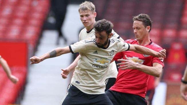 Gelandang Manchester United, Bruno Fernandes (kiri) berduel dengan gelandang Manchester United, Nemanja Matic dalam game internal yang digelar di Old Trafford, Manchester. [Laman resmi Manchester United]