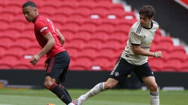 Penyerang Manchester United, Mason Greenwood (kiri) berduel dengan winger Manchester United, Daniel James dalam game internal yang digelar di Old Trafford, Manchester. [Laman resmi Manchester United]