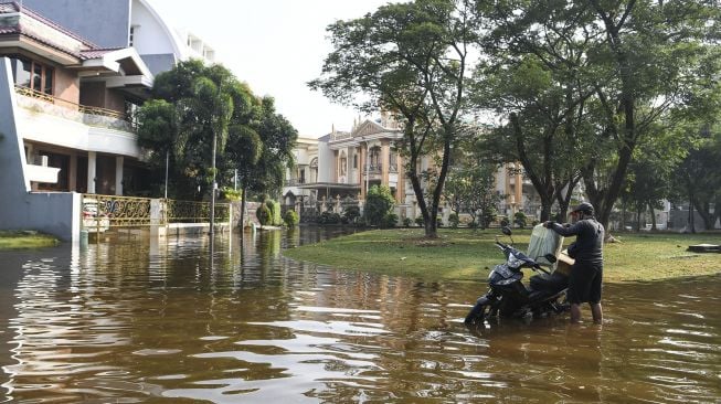 Pengendara motor menata barang bawaannya di atas motor yang mogok akibat banjir rob di Kompleks Pantai Mutiara, Penjaringan, Jakarta, Minggu (7/6). [ANTARA FOTO/Hafidz Mubarak A]