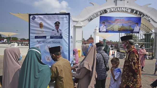 Sejumlah wisatawan antre mencuci tangan sebelum memasuki kawasan wisata religi Kesultanan Banten di Kasemen, Serang, Banten, Minggu (7/6). [ANTARA FOTO/Asep Fathulrahman]