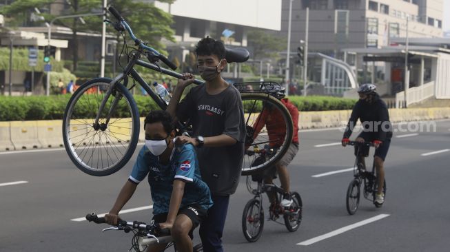 Sejumlah warga berolahraga menggunakan sepeda di Jalan Jenderal Sudirman, Jakarta, Minggu (7/6). [Suara.com/Angga Budhiyanto]