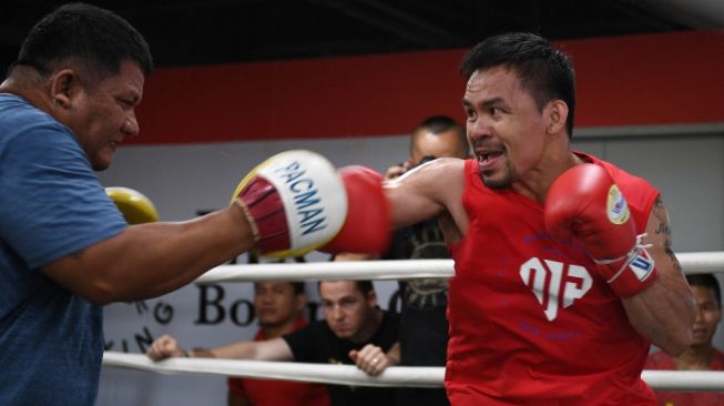 Petinju legendaris dunia Manny Pacquiao (tengah) berlatih bersama pelatihnya, Buboy Fernandez, di sebuah gym di Manila, Filipina, Kamis (17/5/2018). [AFP/Ted Aljibe]