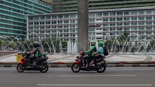 Ojek online membawa penumpang melintas di kawasan Bundaran Hotel Indonesia, Jakarta Pusat, Senin (8/6). [Suara.com/Alfian Winanto]
