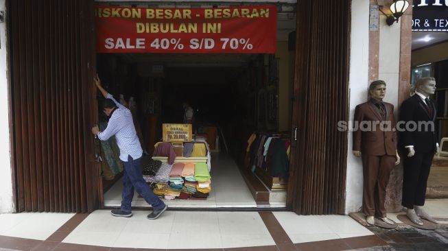 Penjaga toko membuka salah satu toko di Pasar Baru, Jakarta, Selasa (9/6). [Suara.com/Angga Budhiyanto]
