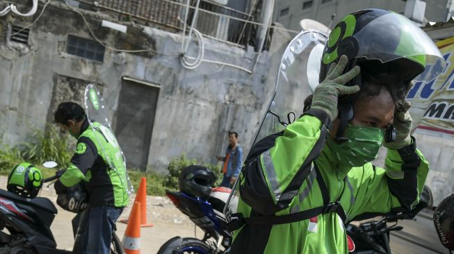 Pengemudi ojek online mengenakan sekat pelindung saat menunggu penumpang di kawasan jalan Kendal, Jakarta, Rabu (10/6/2020).  [ANTARA FOTO/Galih Pradipta]
